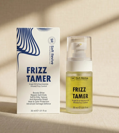 Soft Revive Frizz Tamer hair product shown with its white and blue retail box next to the clear bottle containing pale yellow oil, on a warm beige surface with soft shadows.